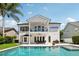 A refreshing backyard pool with patio furniture, a second-story balcony, and lush tropical landscaping at 9684 Sweetleaf St, Orlando, FL 32827