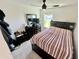Cozy bedroom with a striped bedspread, a ceiling fan, a window with view, and dark wood bedroom furniture at 1116 Myrtle Hammock Ln, Davenport, FL 33837