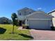Two-story home featuring a well-maintained lawn, brick driveway, and an attached two-car garage at 1116 Myrtle Hammock Ln, Davenport, FL 33837