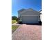 Home featuring a two-car garage, brick driveway, manicured shrubs and grass at 1116 Myrtle Hammock Ln, Davenport, FL 33837