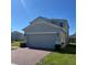 The side of this two-story house features an attached two-car garage and brick driveway at 1116 Myrtle Hammock Ln, Davenport, FL 33837