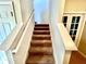 Carpeted staircase with white banisters leading to the upper level of the home and a view of the tile flooring at 1116 Myrtle Hammock Ln, Davenport, FL 33837