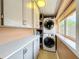 Laundry room with a stacked washer and dryer, storage cabinets, and a window at 1122 Vassar St, Orlando, FL 32804