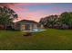 Backyard featuring in-ground pool, covered patio, fire pit, and play set at dusk at 1701 Smoketree Cir, Apopka, FL 32712