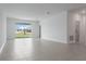 Open living room with gray tile flooring, bright white walls, and sliding glass doors to the backyard at 1908 Blissful Dr, Kissimmee, FL 34744