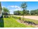 Lawn and landscaping in backyard with sand court visible beyond at 2026 Key Bay Trl, Kissimmee, FL 34747