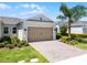 Charming home with a two-car garage, brick driveway, beautiful landscaping, and a mature palm tree at 2026 Key Bay Trl, Kissimmee, FL 34747