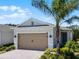 Charming home with a two-car garage, brick driveway, beautiful landscaping, and a mature palm tree at 2026 Key Bay Trl, Kissimmee, FL 34747