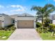 Charming home with a two-car garage, brick driveway, beautiful landscaping, and a mature palm tree at 2026 Key Bay Trl, Kissimmee, FL 34747