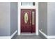 Close-up of the entryway with a maroon front door with decorative glass and side window, stucco, and molding at 346 Willet Ave, Apopka, FL 32703