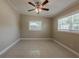 Bright bedroom featuring tile flooring, ceiling fan, and natural light from two windows at 3718 Mitchell Rd, Orlando, FL 32808