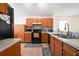 Traditional kitchen features wood cabinetry, black appliances, and tiled floor at 443 S Observatory Dr, Orlando, FL 32835