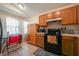 Kitchen area features wooden cabinets, black appliances, and tiled flooring at 443 S Observatory Dr, Orlando, FL 32835