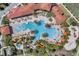 Aerial view of a large community pool area with palm trees, lounge chairs, a splash pad, and a water slide at 4722 Terrasonesta Dr, Davenport, FL 33837