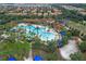 Aerial view of a community pool with lounge areas, a playground, and a clubhouse surrounded by palm trees at 4722 Terrasonesta Dr, Davenport, FL 33837
