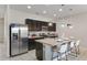 Open kitchen with dark cabinetry, stainless steel appliances, granite countertops, and seating at the island at 4722 Terrasonesta Dr, Davenport, FL 33837