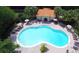 Aerial view of a large community pool with lounge chairs and umbrellas surrounded by mature trees at 5123 Crown Haven Dr, Kissimmee, FL 34746