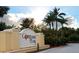 Community entrance sign under a partly cloudy sky featuring lush landscaping and mature palm trees at 5123 Crown Haven Dr, Kissimmee, FL 34746