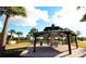Community gazebo featuring picnic tables and a brick patio surrounded by palm trees and a grassy park area at 5123 Crown Haven Dr, Kissimmee, FL 34746