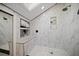 Modern shower with marble walls, a black shower head, built-in shelves, and mosaic tile flooring at 677 Benitawood Ct, Winter Springs, FL 32708