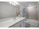 Bathroom boasting a shower with a neutral shower curtain, white cabinets, and vanity mirror at 7649 Ragusa Way, Clermont, FL 34714