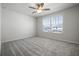 Bright bedroom with plush gray carpeting, ceiling fan, and a sunlit window at 7649 Ragusa Way, Clermont, FL 34714
