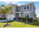 Inviting two-story home featuring lush green lawn and tropical palm tree at 7649 Ragusa Way, Clermont, FL 34714