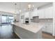 Bright, white kitchen features an island with sink, pendant lighting and sliding glass doors to the patio at 7649 Ragusa Way, Clermont, FL 34714