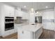 Bright, white kitchen features a large island, stainless steel appliances, and stylish pendant lighting at 7649 Ragusa Way, Clermont, FL 34714