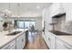Bright, white kitchen features stainless appliances, cooktop, wall ovens and large island overlooking dining area at 7649 Ragusa Way, Clermont, FL 34714