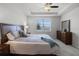 Comfortable main bedroom with tray ceiling, ceiling fan, large window, and stylish furnishings at 7649 Ragusa Way, Clermont, FL 34714