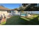 Backyard view of the inviting in-ground pool and manicured lawn surrounded by a white fence at 7730 Broken Arrow Trl, Winter Park, FL 32792