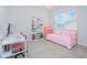 Brightly lit bedroom featuring pink daybed, white shelving, and large window at 7831 Dausset St, Orlando, FL 32827