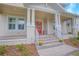 Inviting covered front porch with detailed stonework, white columns, a red front door, and manicured landscaping at 7831 Dausset St, Orlando, FL 32827