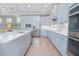 Open kitchen featuring light gray cabinets, quartz countertops, stainless appliances, and hardwood flooring at 7831 Dausset St, Orlando, FL 32827