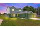 Two-story home with gray roof and fresh green paint features an attached garage and green lawn at twilight at 905 Ocala Woods Ln, Orlando, FL 32824