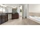 A bathroom offers a tiled floor, double vanity with dark cabinets, large tub, and views of the backyard pool at 12222 Cypress Landing Ave, Clermont, FL 34711