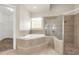 An elegant bathroom features a garden tub with steps leading to it, as well as a glass enclosed shower at 12222 Cypress Landing Ave, Clermont, FL 34711