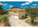 Two-story yellow house boasts a tile roof, a three car garage, and manicured landscaping at 12222 Cypress Landing Ave, Clermont, FL 34711