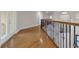 This hallway includes hardwood floors, dark iron decorative railings, and light neutral paint at 12222 Cypress Landing Ave, Clermont, FL 34711