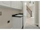 Laundry room with a sink and cabinets adjoins a tiled foyer with stairs leading to the second story at 12222 Cypress Landing Ave, Clermont, FL 34711