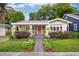 Charming bungalow with lush landscaping, featuring colorful flowers and a welcoming orange front door at 14 N Lawsona Blvd, Orlando, FL 32801