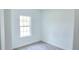 A white bedroom with a window and gray wood floors at 16908 Sw 44Th Cir, Ocala, FL 34473