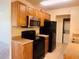 Functional kitchen featuring wooden cabinets, black appliances, and a view into the laundry area at 1695 Lee Rd # E214, Winter Park, FL 32789