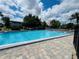 A shared community pool with clear blue water surrounded by a paver deck and mature trees at 1695 Lee Rd # E214, Winter Park, FL 32789
