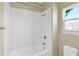 Bathroom featuring a white tiled shower-tub combination and a window at 17117 Cypress Preserve Pkwy, Orlando, FL 32820