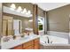 Luxury bathroom featuring dual vanity, soaking tub and a window with natural light at 17117 Cypress Preserve Pkwy, Orlando, FL 32820