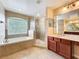 Bright bathroom with a soaking tub under a window and a glass-enclosed tiled shower at 2145 Plantation Oak Dr, Orlando, FL 32824