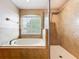 Bathroom featuring a tub under a window next to a glass enclosed shower with tiled walls at 2145 Plantation Oak Dr, Orlando, FL 32824