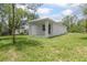 Backyard view of a white single-story house with a white roof, green grass, and shady trees at 2259 3Rd Ave, Deland, FL 32724